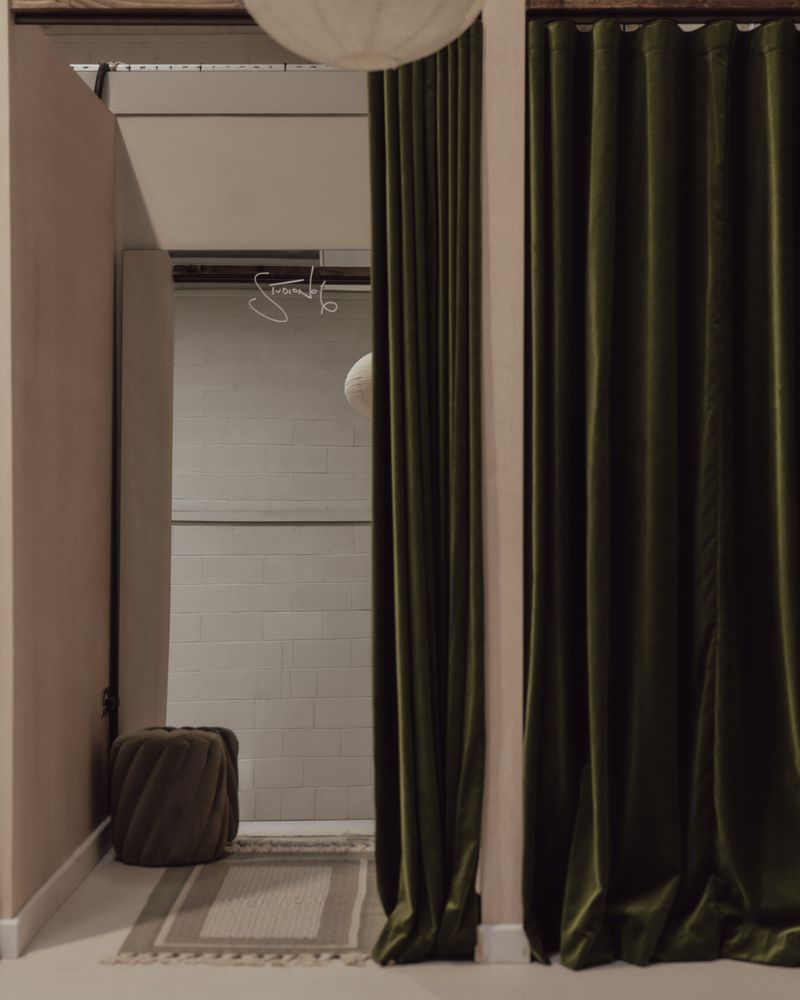 Curtained changing bay with a velvet pouffe and woven rug.