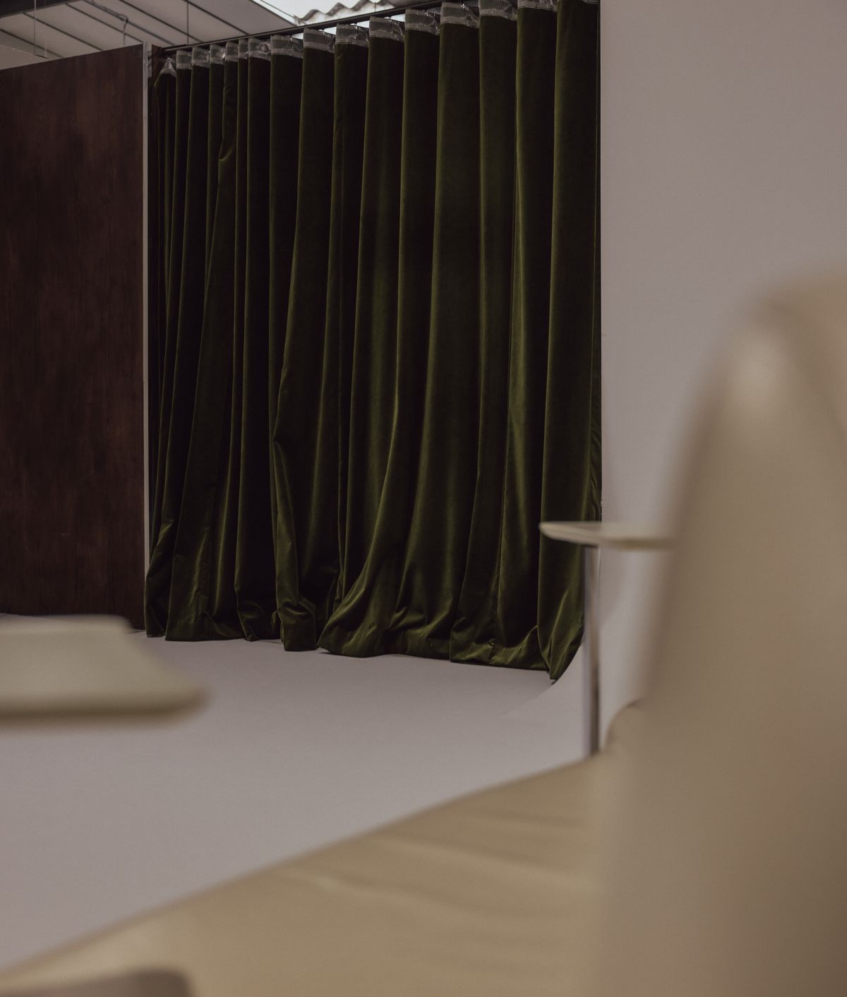 Olive velvet curtain seen past cream leather seating.