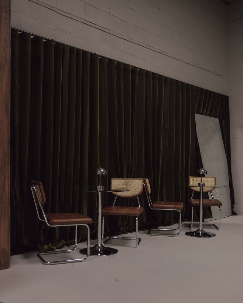 Cane and leather chairs arranged along the olive curtain wall.