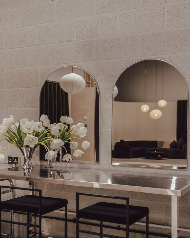 Arched mirrors and white tulips on the steel styling console.